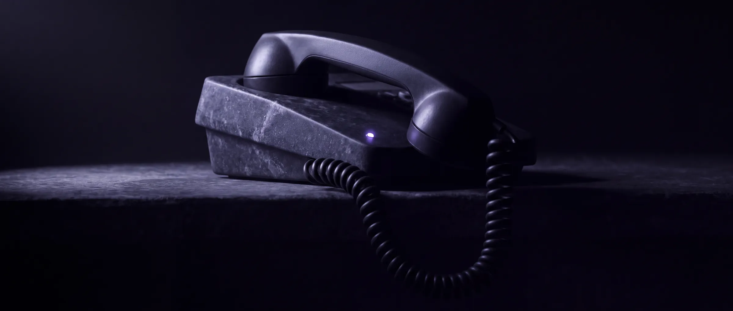 A private line handset off its cradle on dark stone