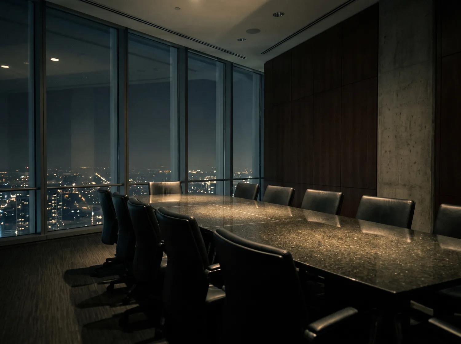 An empty boardroom at night high above a dark city