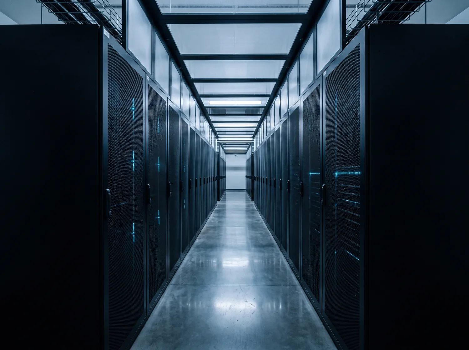 The cold aisle of a data hall, two facing rows of server cabinets receding to a vanishing point